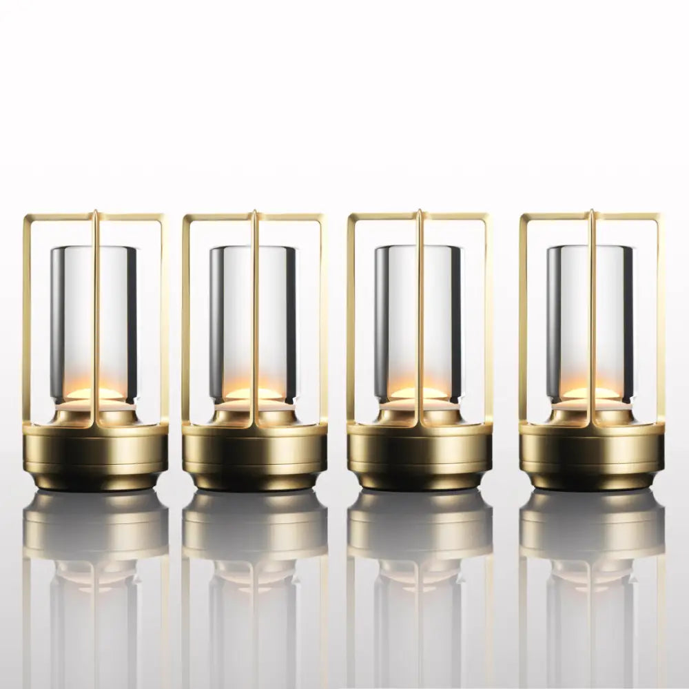 Four gold-toned DecorBites™ nordic rechargeable table lamps with clear glass cylinders and warm internal lighting
