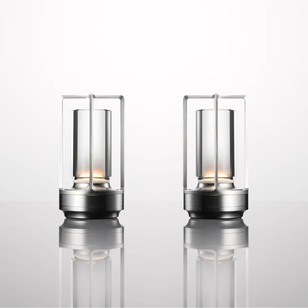 Two nordic rechargeable table lamps with brushed stainless steel frames and clear glass enclosures housing warm led lights