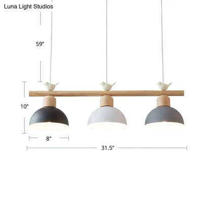 Modern three-light hanging island light with natural wood bar, black white and gray metal dome shades, and ceramic bird decor