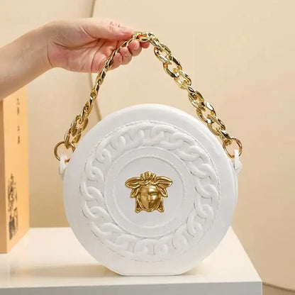 White circular handbag with gold-tone chain strap and embossed medusa head clasp styled with nordic style flower vase decor