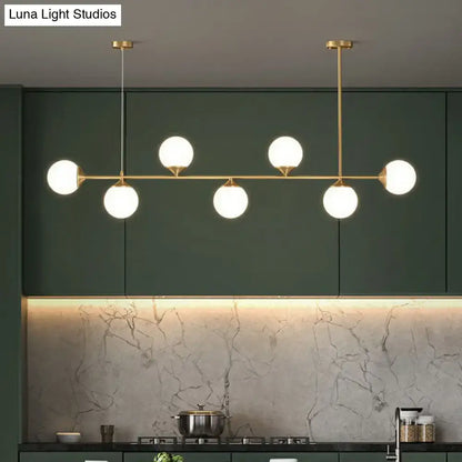 Modern brass pendant light with six white opaline glass globes for minimalist dining room island lighting