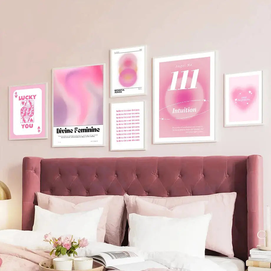 A collection of six framed pink angel number posters with white designs arranged above a tufted rose-colored headboard
