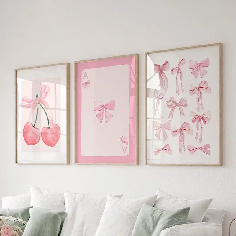 Three framed pink bows wall art set with cherries and playing cards prints displayed above a bed by DecorBites™