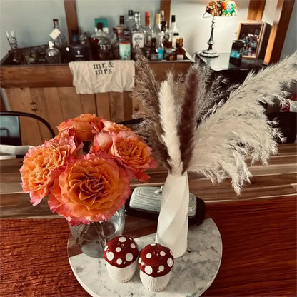 DecorBites™ plastic flower vases feature a white twisted ceramic design holding pampas grass and orange roses
