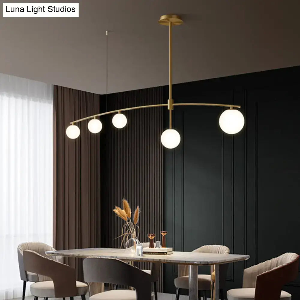 DecorBites postmodern gold island pendant light with five frosted white glass orb bulbs in curved arc hanging lamp design