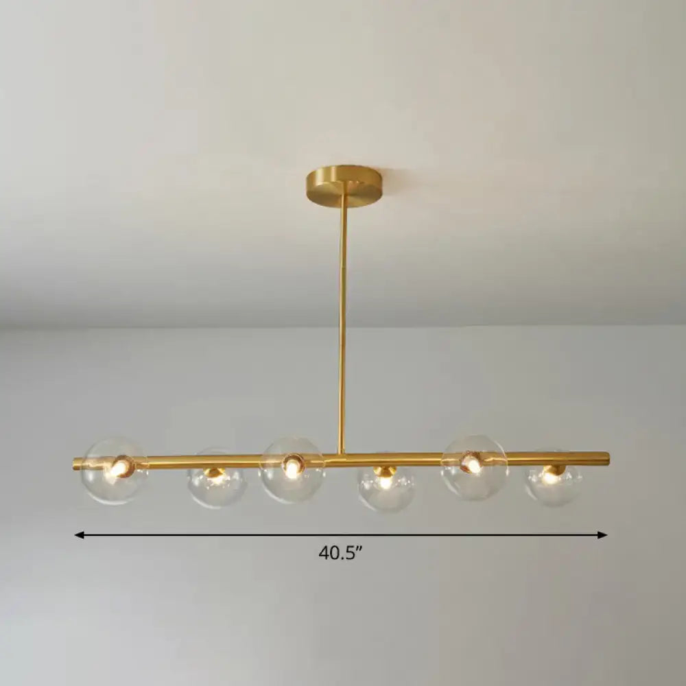 Gold-toned brass pendant light with five clear glass globes and linear island lamp design for dining room by DecorBites™