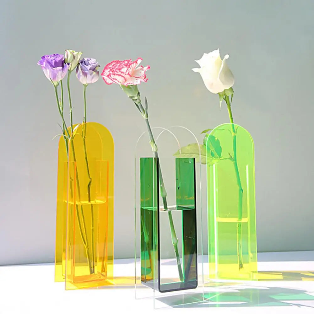 Three translucent rainbow color acrylic flower vases in nordic style with arched tops holding fresh flowers