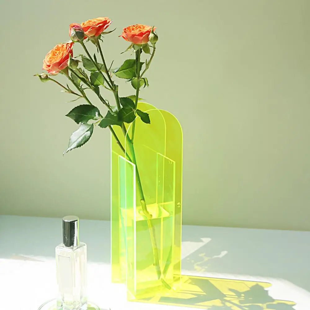 A translucent lime-green rainbow color acrylic flower vase with a modern nordic style design holding orange roses