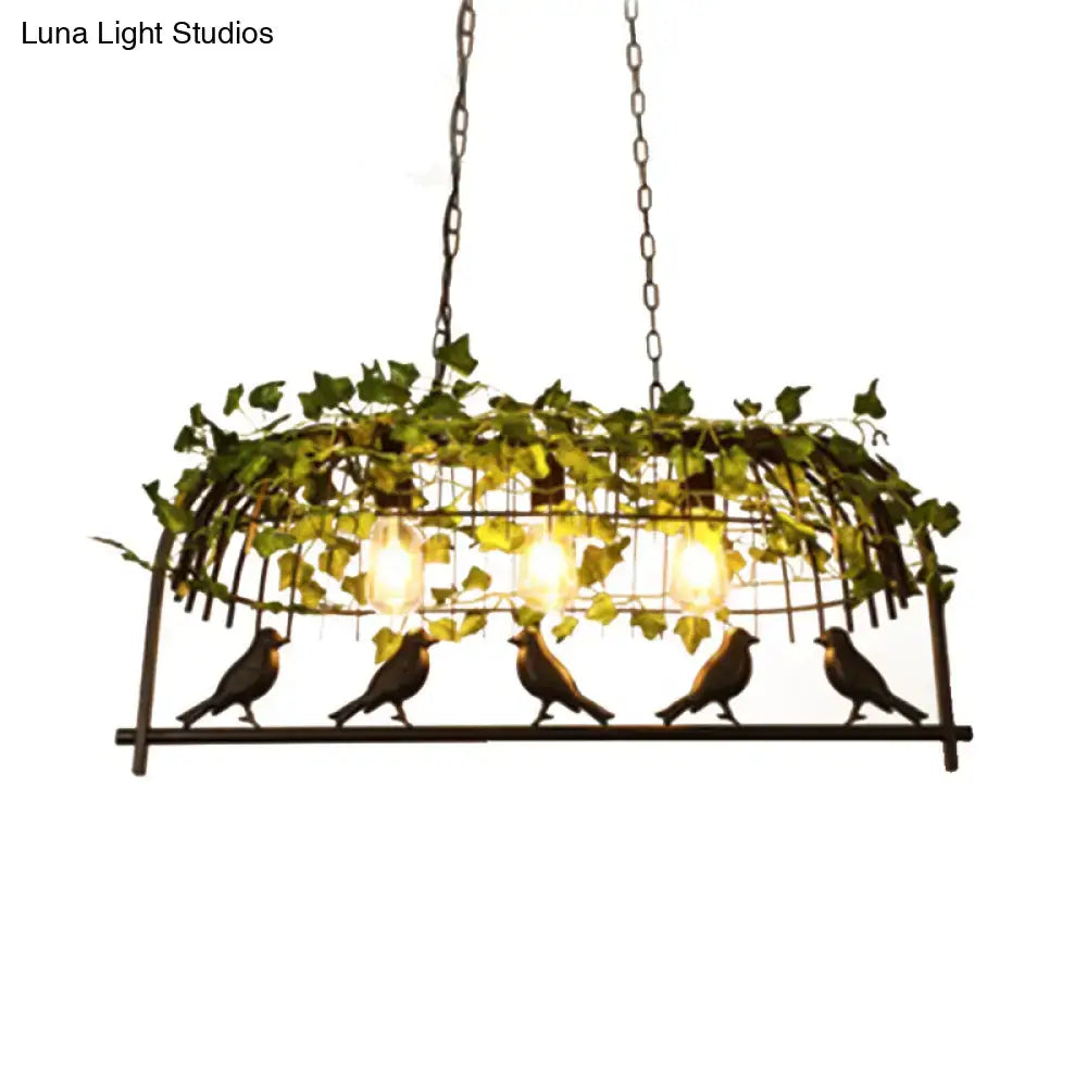 Wrought iron black retro birdcage island light fixture with ivy and bird motifs and warm glowing bulbs