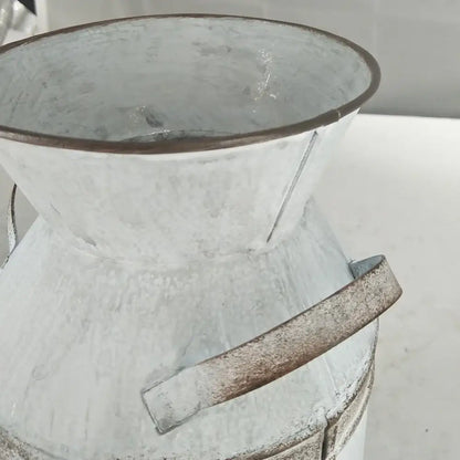 A rustic white galvanized metal vase holder with a weathered finish and sturdy handle for wedding garden decor