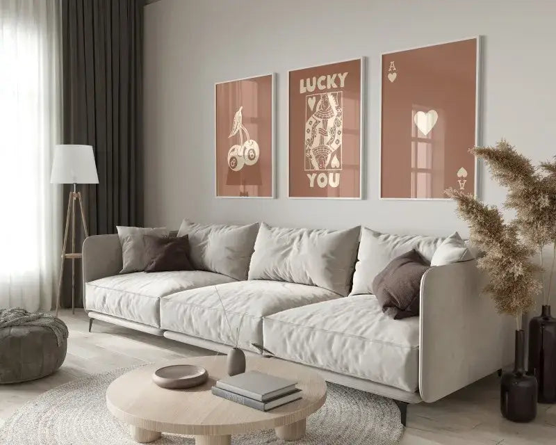 Light gray upholstered sectional sofa with dark brown throw pillows and sleek metal legs beside DecorBites™ retro wall art set queen of hearts theme