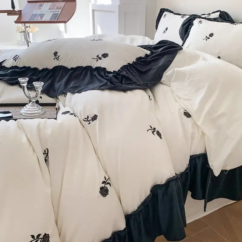 Cream-colored DecorBites™ rose embroidered duvet cover set with black floral embroidery and navy blue ruffled trim