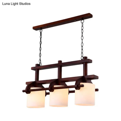 Dark wood-framed pendant island light with three white glass shades suspended by black chains for dining room use
