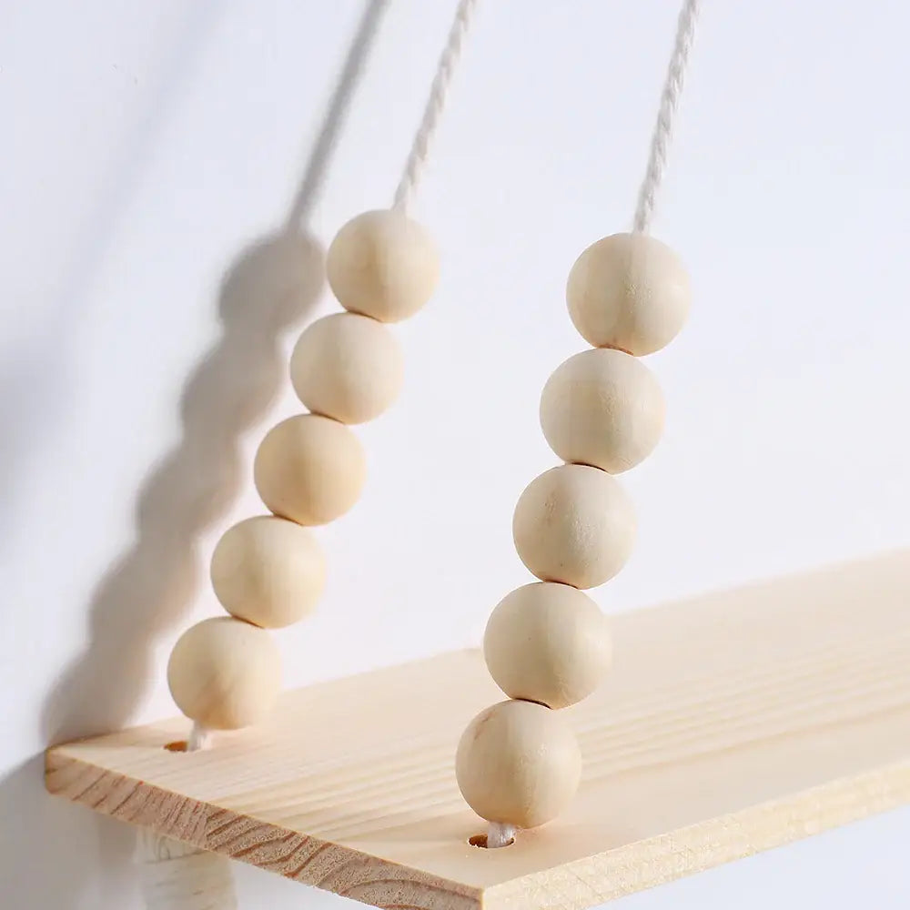 Light-colored wooden bead swing hanging from a rustic wooden wall shelf with plant storage by decorbites