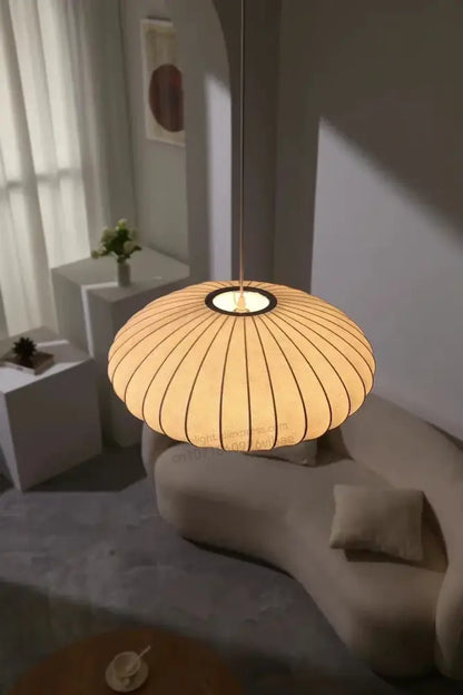 Warm-toned silk led pendant lamp with ribbed paper shade and sleek black circular base by decorbites modern lighting