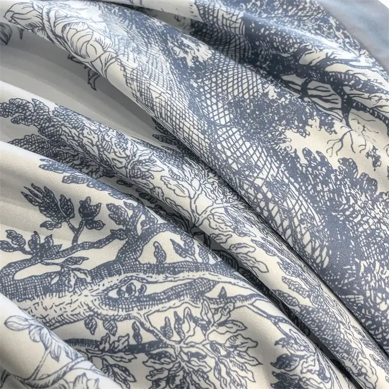 Cream-colored eucalyptus fiber duvet cover with detailed blue toile pattern featuring trees and foliage from decorbites