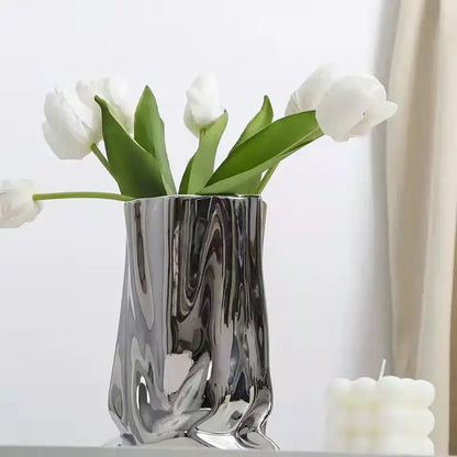 A sleek silver ruffled ceramic flower vase by DecorBites holding white tulips with a fluid sculpted design