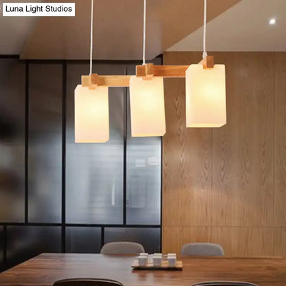 Modern minimalist pendant light with three rectangular opaline glass shades and adjustable chain cord length on wooden crossbar