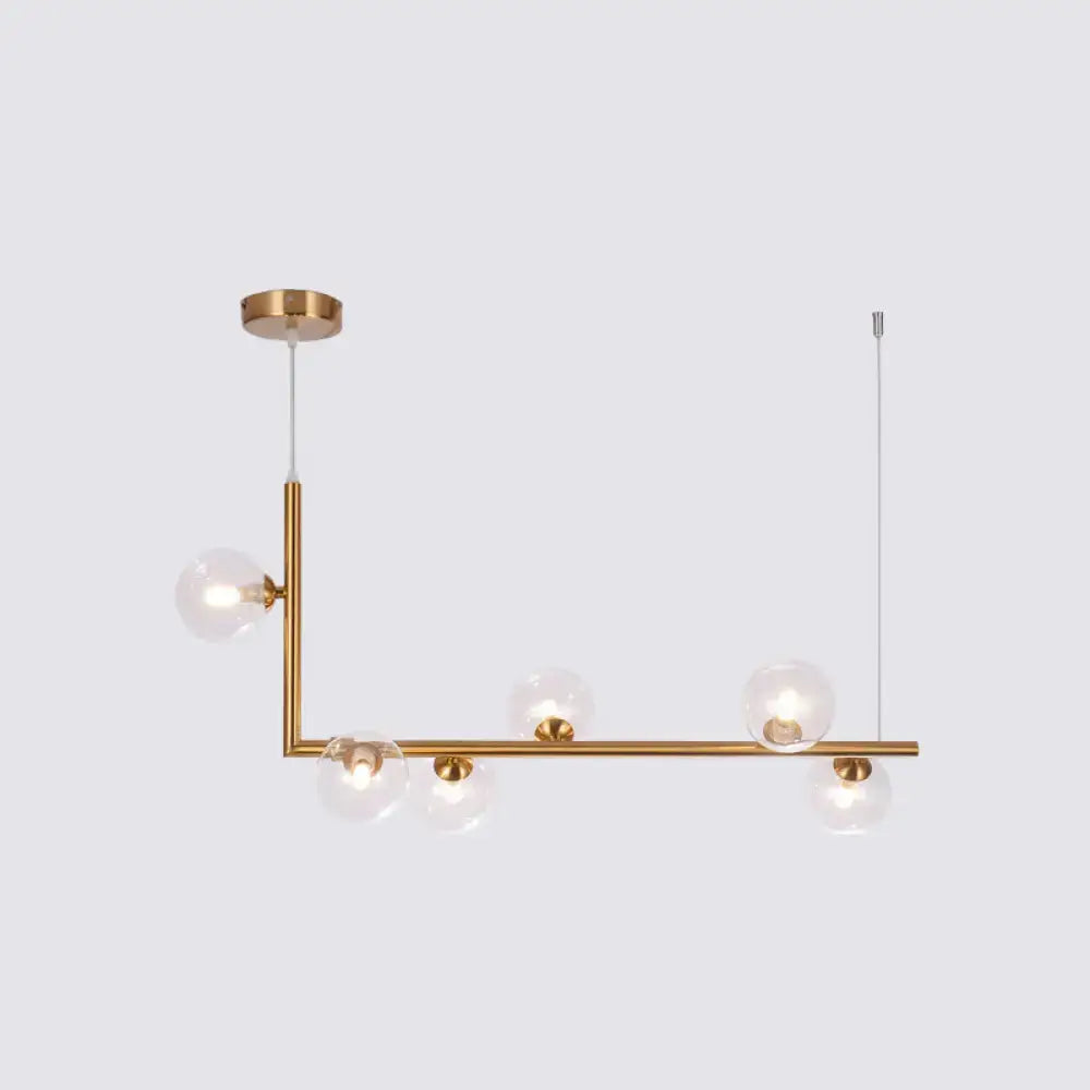 Modern gold-toned linear pendant light with clear glass globe bulbs for dining room hanging island by DecorBites