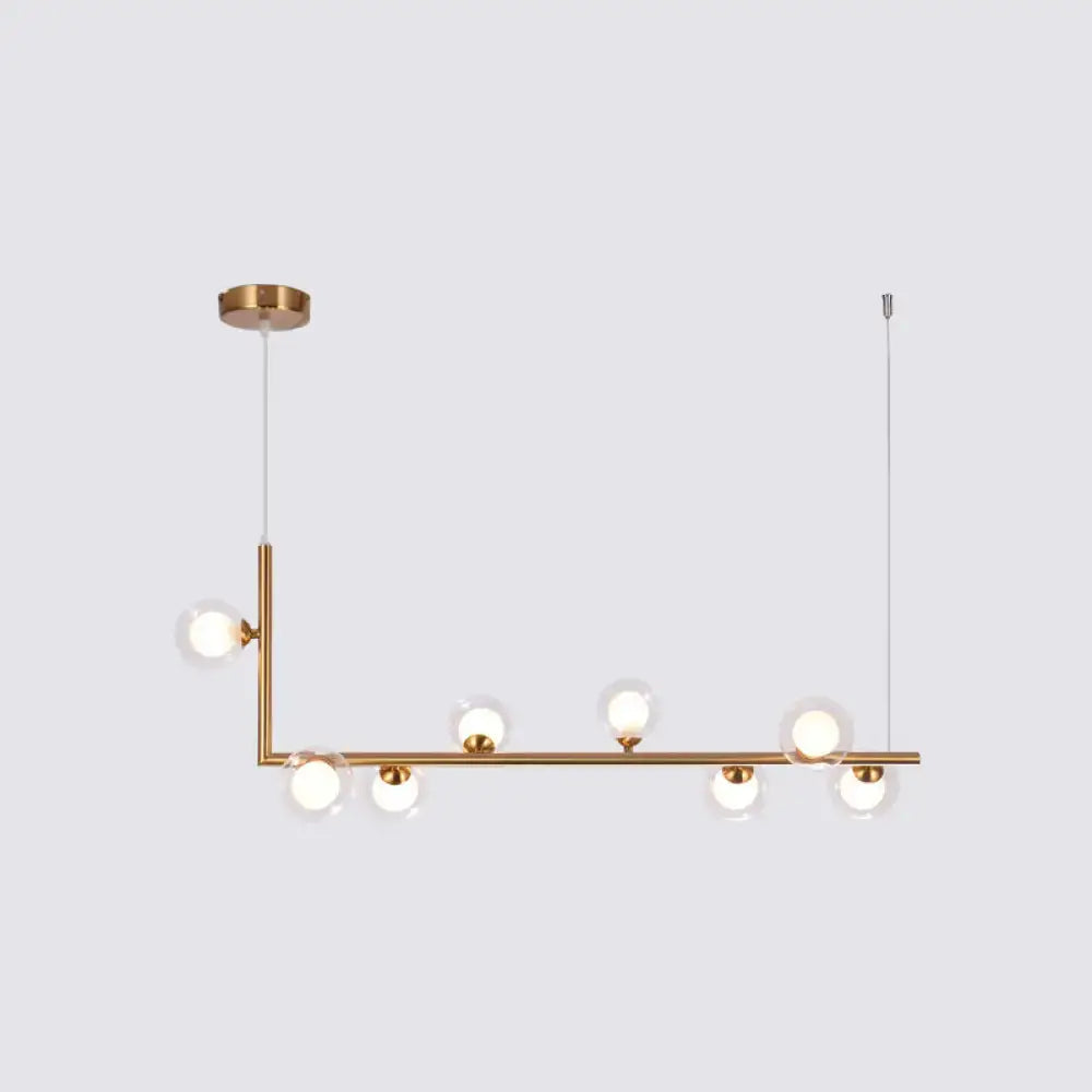 Modern brass pendant light with six clear glass globes on a sleek linear frame for dining room hanging island