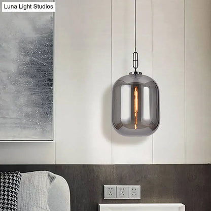 A decorbites smoke gray and cognac glass pendant lamp with a modern cylindrical design and visible filament bulb