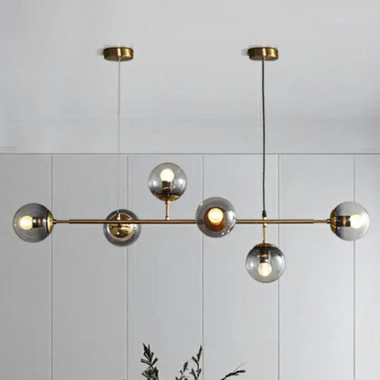 Modern brass finish pendant light with smoke grey glass and six spherical bulbs ideal for restaurants