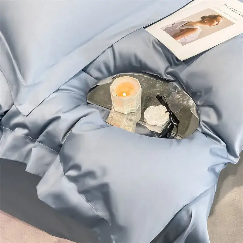 A small round mirrored tray with a lit candle and black glasses on soft egyptian cotton duvet cover bedding set