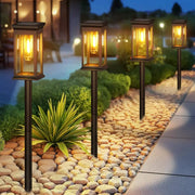Four black solar lights pack with warm yellow glass panels and visible filament bulbs super bright 12hrs decorbites