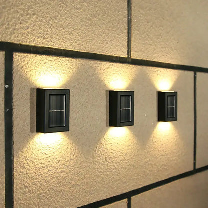 Three black rectangular DecorBites™ solar outdoor led lights with warm yellow light for garden decoration