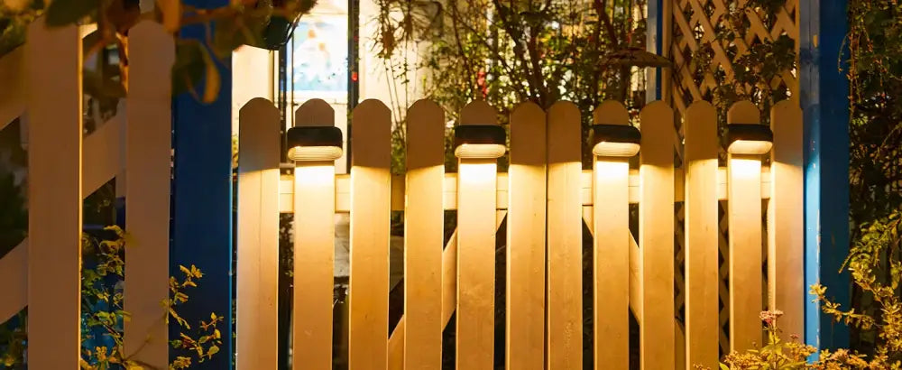 DecorBites solar powered white picket fence lights emitting warm glow for yard deck and patio illumination