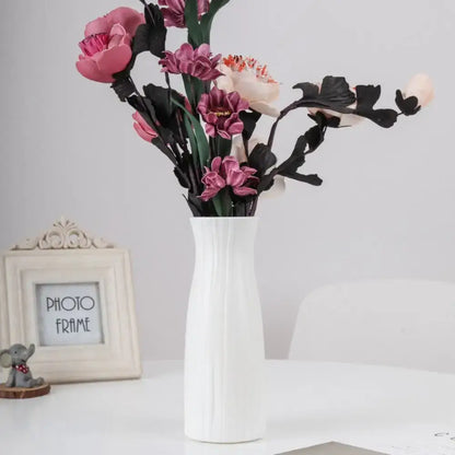 White ceramic solid color plastic flower vase with vertical ridged texture holding pink purple and cream artificial flowers