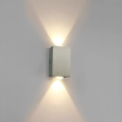 Modern brushed aluminum sphera wall sconces by decorbites with two angled lights casting warm illumination