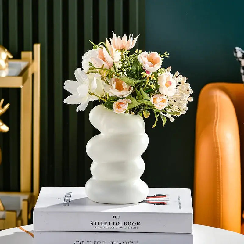 DecorBites™ spiral white vase in ceramic with wavy segmented design holding peach and cream artificial flowers