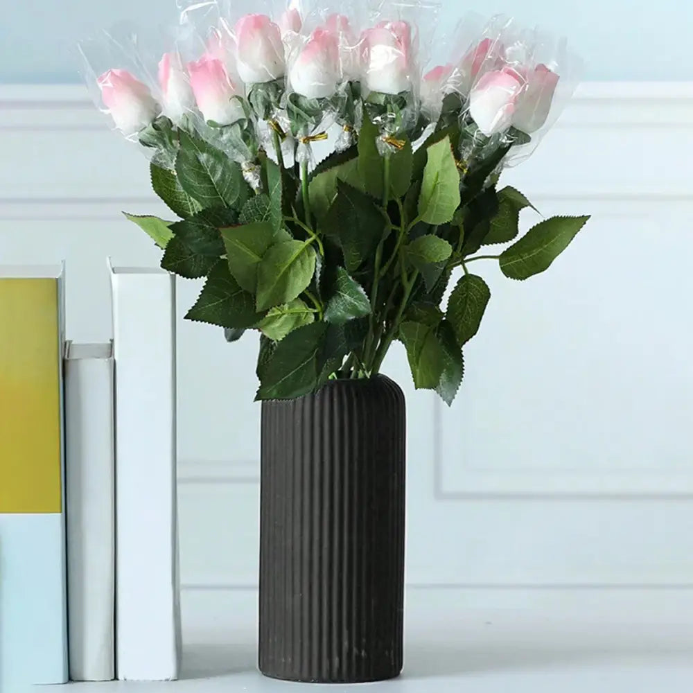 A bouquet of pink and white artificial roses in a dark brown decorbites striped ceramic-like plastic vase