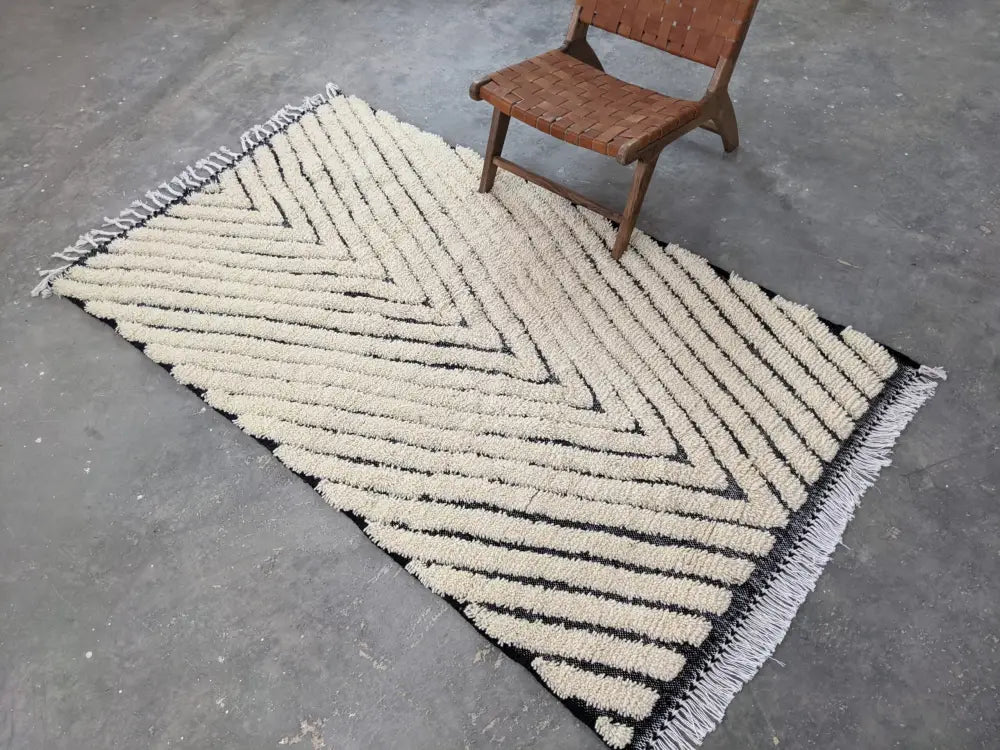 Cream-colored textured tapis beni with bold black chevron stripes and white fringe edges by decorbites™ beni ouarain