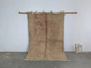Beige plush wool tapis beni ouarain with fringed edges hanging on wooden rod from decorbites collection