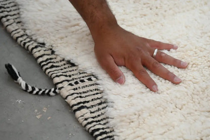 A plush white beni ouarain tapis beni with bold black and white striped fringe measuring 290 x 205 cm
