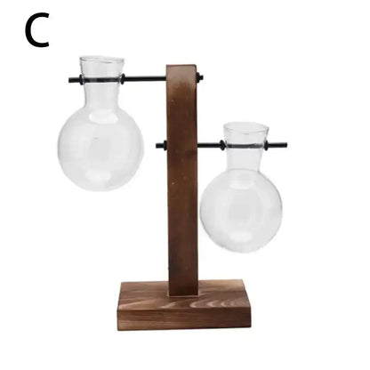 Wooden stand holding two clear glass round-bottomed flasks for avocado seed starter by DecorBites™