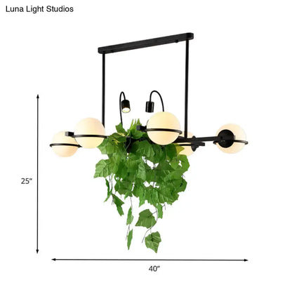 Black metal chandelier island lighting fixture with five frosted glass globes and hanging green vine by DecorBites™
