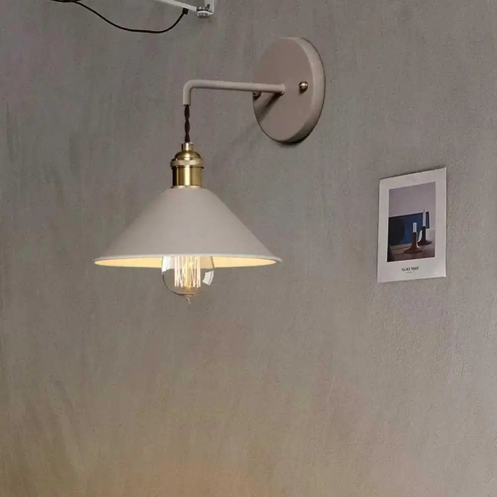 A minimalist white conical shade vintage plated wall lamp with a brass-finished base and exposed filament bulb by decorbites