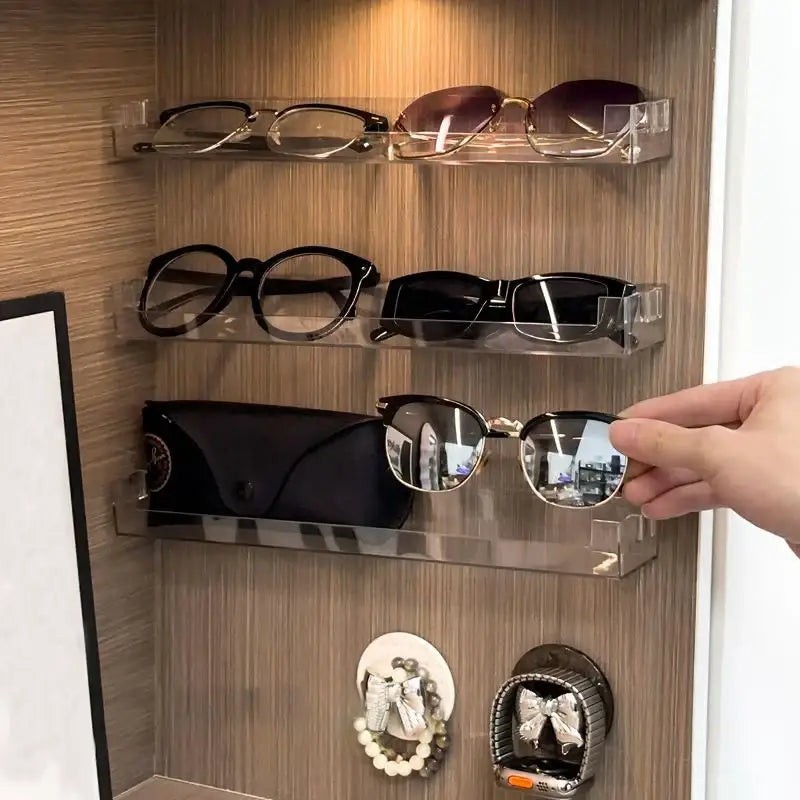 DecorBites wall mounted transparent acrylic storage rack holding multiple pairs of eyeglasses and sunglasses