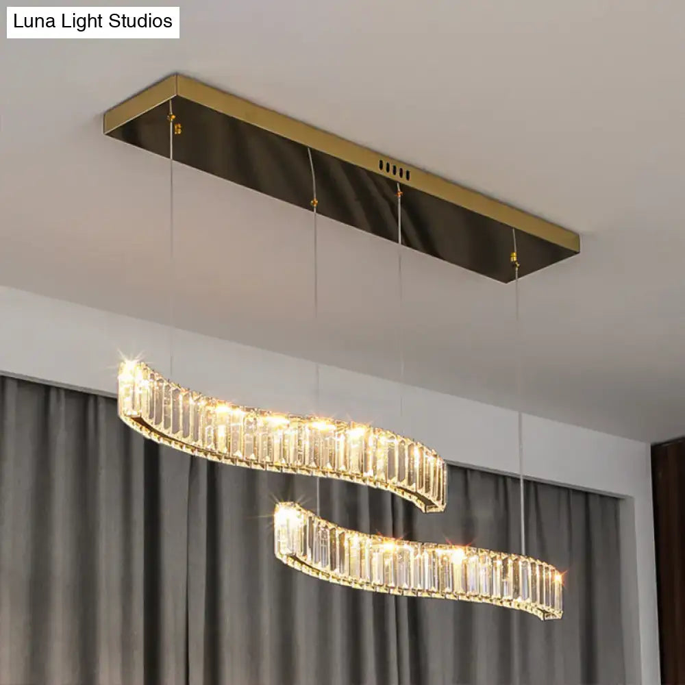 Gold-toned rectangular ceiling fixture with two curved illuminated prismatic crystal chandeliers in brass finish for restaurants