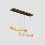 Modern gold-toned rectangular pendant light with two curved prismatic crystal tiers in brass finish for restaurants