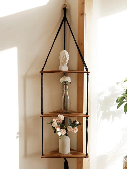 Black macrame cord suspends three wooden triangular shelves in a decorbites wooden corner shelf boho wall decor