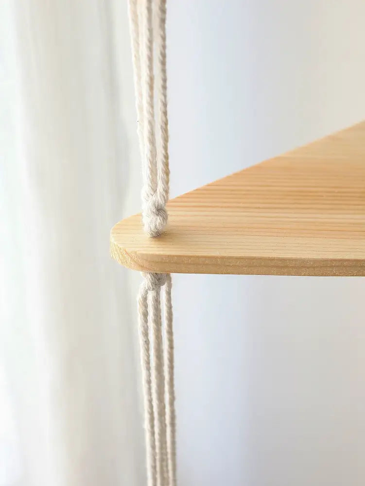 Decorbites™ wooden corner shelf featuring a light wood triangular design with cream macrame cords for boho decor