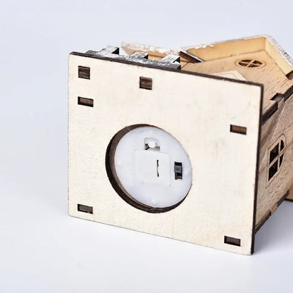 A light-up wooden led light house piggy bank by decorbites with small windows and a battery compartment visible
