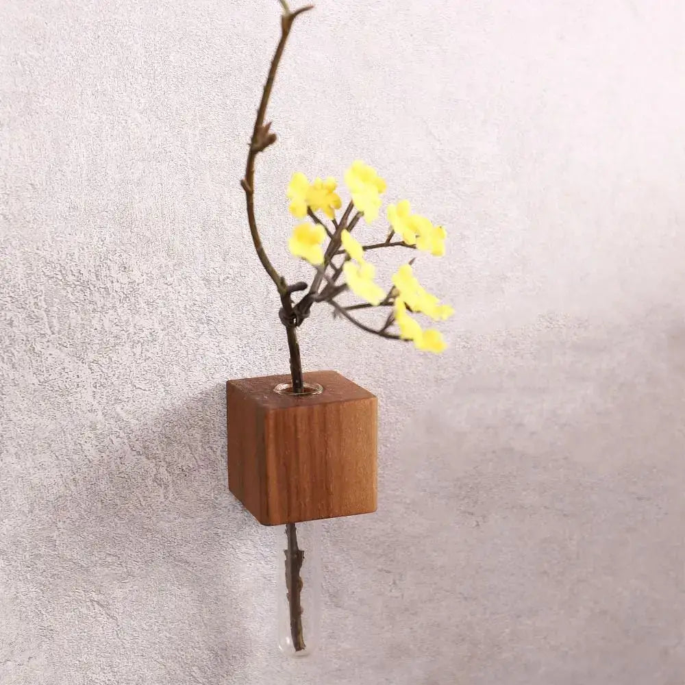 DecorBites wooden magnetic test tube vase mounted on wall holding a branch with bright yellow artificial flowers
