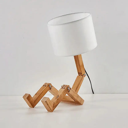 Minimalist wooden robot shape table lamp with white cylindrical shade and articulated legs for indoor study use