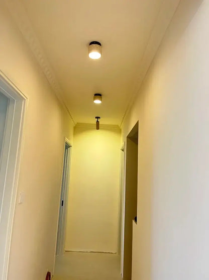 Two cylindrical recessed ceiling lights with black fixtures and warm white illumination in DecorBites yellow marble ceiling light design