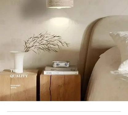 White ceramic vase with slender neck and flared rim holding dried branches near yellow stone led pendant chandelier
